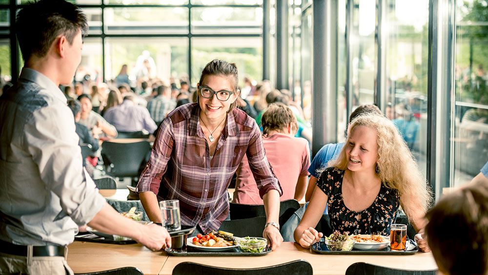 Studenten in einer Mensa an einem Tisch.