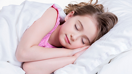 The image shows a young girl sleeping in her bed.