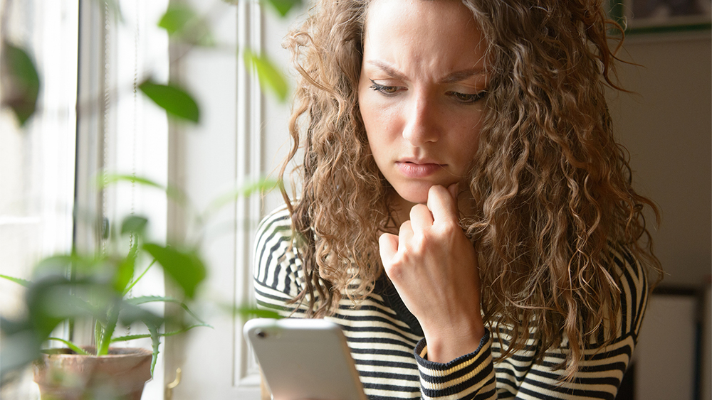 Skeptische Frau vor Handy